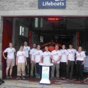 Group of QineteQ workers who arrived at Lyme Regis RNLI lifeboat station at the end of a hike through Dorset which raised £1,600 for the life-saving charity