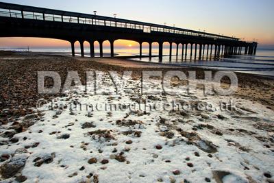 Sunrise over  Boscombe beach and pier with a sprinking of snow on the beach. 