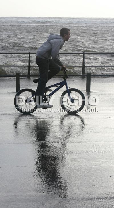 Stormy weather ... A cyclist out in the storm at Mudeford Quay