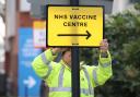 A Brent Council worker hangs a direction sign to the NHS Covid Vaccine Centre at the Olympic Office Centre, Wembley, north London, as ten further mass vaccination centres opened in England with more than a million over-80s invited to receive their