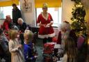 Father Christmas (aka the Mayor of Lyme Regis David Sarson) and his helper, vice-chairman Francesca Evans, handing out presents at the Lyme Regis Football Club Christmas Party. Photo: Lyme Regis Football Club.
