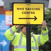 A Brent Council worker hangs a direction sign to the NHS Covid Vaccine Centre at the Olympic Office Centre, Wembley, north London, as ten further mass vaccination centres opened in England with more than a million over-80s invited to receive their