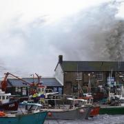 Waves crash against the cobb in Lyme Regis during Storm Eustice (PA)