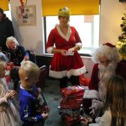 Father Christmas (aka the Mayor of Lyme Regis David Sarson) and his helper, vice-chairman Francesca Evans, handing out presents at the Lyme Regis Football Club Christmas Party. Photo: Lyme Regis Football Club.