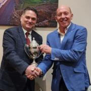 Mike Savage, right, collects the Champion of Champions trophy from Spike Spiller, left